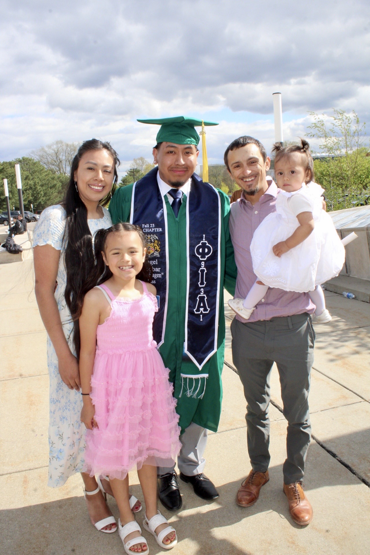 First-generation graduate celebrating commencement with family and young children